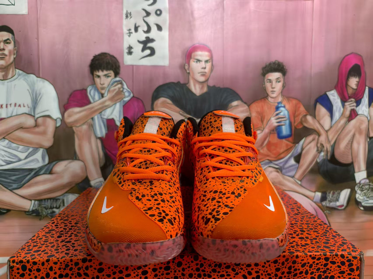 Front view of orange Nike sneakers with black leopard print, orange laces, and translucent soles.