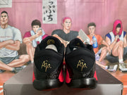 Rear view of the sneakers showing black heels with gold-colored decorative lettering.