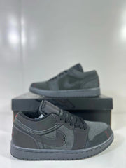 Close side view of dark grey and black sneakers with subtle red details