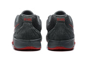 Rear view of the dark gray sneakers showing padded collars, stitched heel panels, and red outsole edges.