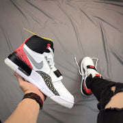Angled side view showing the gray side Swoosh, elephant-print overlay, red heel panel, and white outsole.