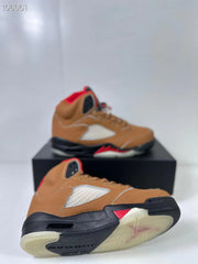 Angled view of the brown high-top sneakers showing the outsole, side panel, and red midsole detailing.