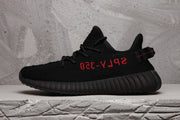 Side profile of a black knit-style sneaker with red side lettering and a ribbed black sole.