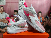 Angled view of white and pink Nike basketball shoes showing side panels and patterned outsole