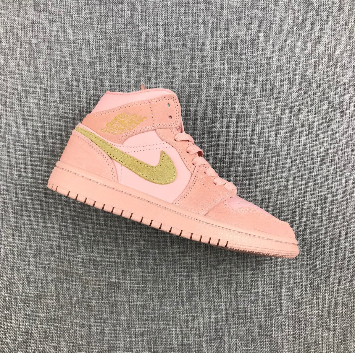 Side view of a pink Jordan high-top sneaker with an olive-green Swoosh and pink outsole.