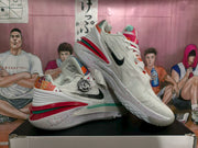 Pair of white Nike basketball sneakers with black Swooshes, multicolor accents, red and green outsole details, and speckled midsoles.