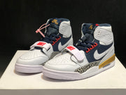 Front three-quarter product view showing the white and navy upper, red lace details and elephant-print side panels.