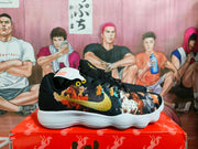 Side view of a black Nike sneaker with a gold Swoosh, multicolor graphic detailing, black heel panel, and white outsole.