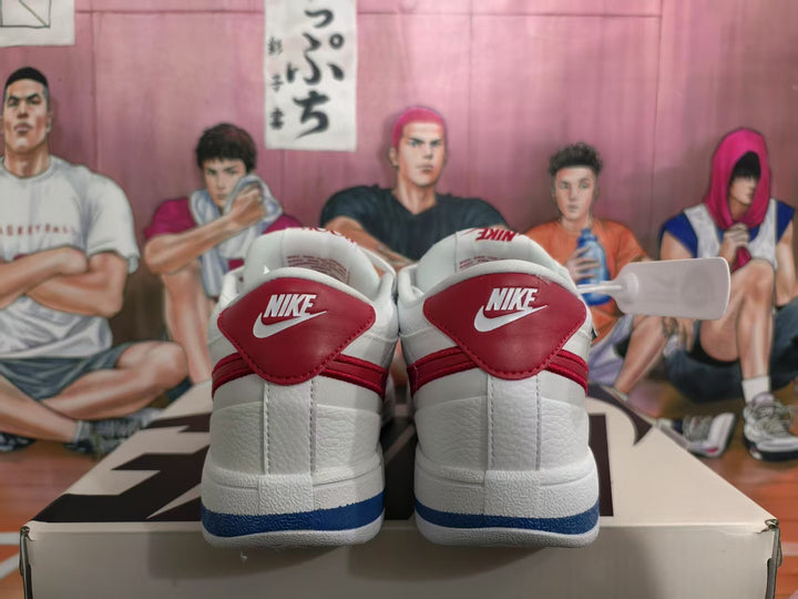 Rear view of white Nike sneakers with red heel panels and blue outsole detailing.