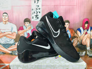 Black Nike low-top sneakers with white side swooshes, black laces, and glossy sculpted soles.