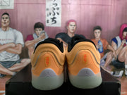 Rear view of the orange sneaker pair showing heel branding and translucent-looking light gray outsoles.