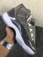 Side view highlighting the grey upper, glossy dark overlay, white midsole, and translucent outsole.