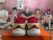 Rear view of red, white, and gold basketball sneakers displayed on an orange shoebox.