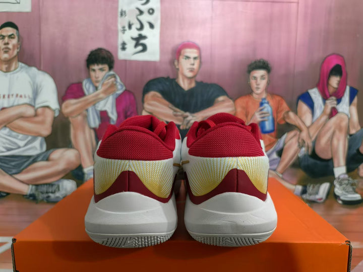 Rear view of red, white, and gold basketball sneakers displayed on an orange shoebox.