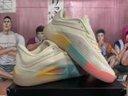 Angled view of the beige Jordan basketball sneakers highlighting the textured side panels and contrasting yellow, teal, and pink sole sections.