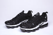 Pair of black and white Nike TN-10 sneakers in a front three-quarter view.