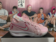 Close side view of pink Nike sneakers showing the perforated upper, lace system, red Swoosh, floral outsole graphics, and ZoomX midsole branding.