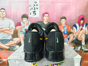 Rear view of black Nike Kobe basketball shoes with gold accents and glossy black soles