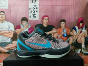 Side view of a gray basketball sneaker with a textured patterned upper, blue side logo, black laces, and light-colored outsole.