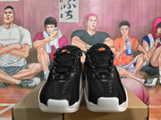 Front view of black Nike sneakers with mesh uppers, black laces, and orange tongue accents.