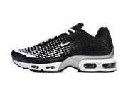 Side view of a black and white Nike Air Max Plus VII sneaker with dotted gradient detailing and visible sole cushioning windows.