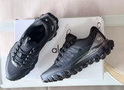 Pair of black Alo hiking sneakers displayed on a branded box, showing the top and side profiles.