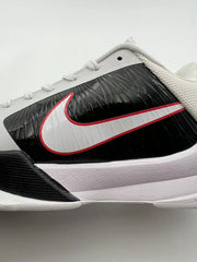 Side close-up of the white Swoosh over a glossy black panel with a pale midsole