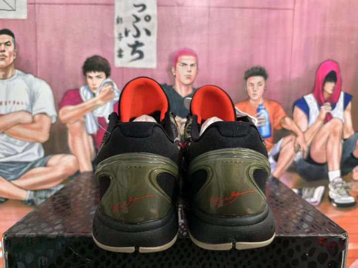 Rear view of black and olive Nike basketball sneakers with red detailing and translucent olive heel sections.