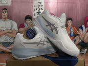 Angled side view of white ASICS basketball shoes with gray side logos and pale blue-gray midsoles.