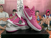 Angled view of a pair of pink and white basketball sneakers showing the textured uppers, silver accents, white midsoles, and pink outsole details.