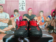 Front view of the black and red sneakers, showing the red laces, textured toe boxes, and patterned outsoles.