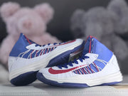 Pair of white, blue, and red high-top shoes shown from the side