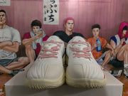 Front view of the white sneakers with red-and-white patterned laces and red accents.