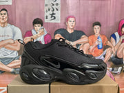 Side profile of a black Nike sneaker showing the visible swoosh, glossy side panel, textured upper, and oval sole details.