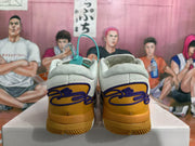 Rear view of white and gold Nike basketball sneakers with purple detailing and padded collars.
