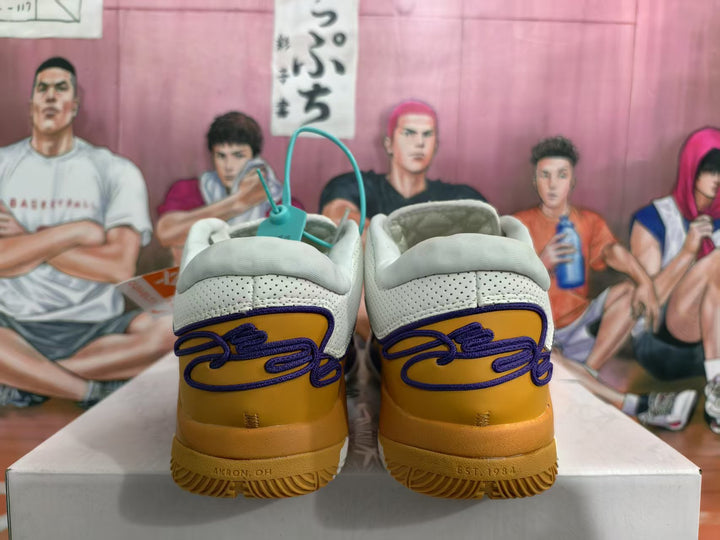 Rear view of white and gold Nike basketball sneakers with purple detailing and padded collars.