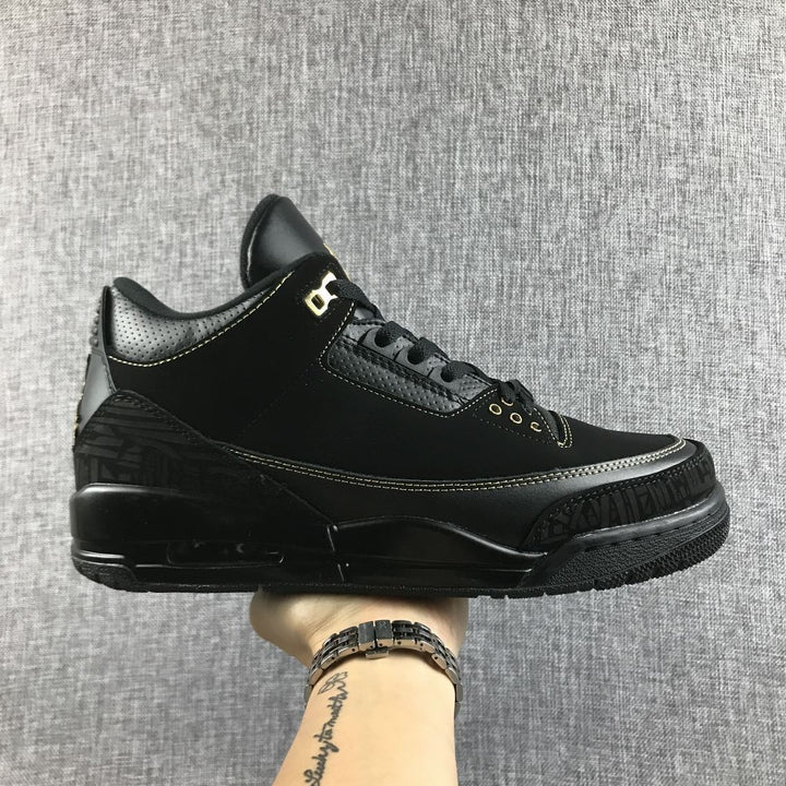 Side view of a black Jordan Air Jordan 3 BHM sneaker with gold accents