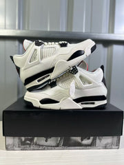 Pair of white and black Air Jordan 4 sneakers arranged on a black shoebox, showing both lateral sides.