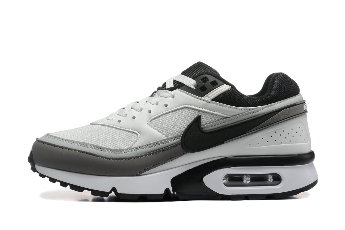 Side view of a white, grey and black Nike-branded sneaker with mesh panels and visible heel cushioning.