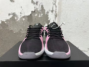 Front view of pink and black low-top basketball shoes with black laces and white midsoles.