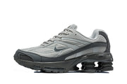 Side view of a grey Nike Shox Ride 2 sneaker with dark grey panels and sculpted cushioning columns.