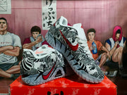 Angled view of zebra-print Nike basketball sneakers displaying the patterned upper, red Swoosh, white laces, and textured outsole.