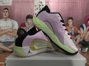 Two lavender-pink sneakers shown from the side and outsole, highlighting the black collar, green midsole, and layered side detailing.