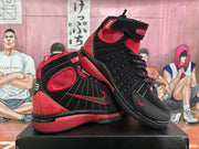 Three-quarter view of black and red high-top sneakers showing the ankle straps, side details, padded collars, and red outsole accents.