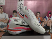 Angled view of white Nike GT sneakers showing the lace-up upper, black Swoosh, pink accents, and speckled midsole.