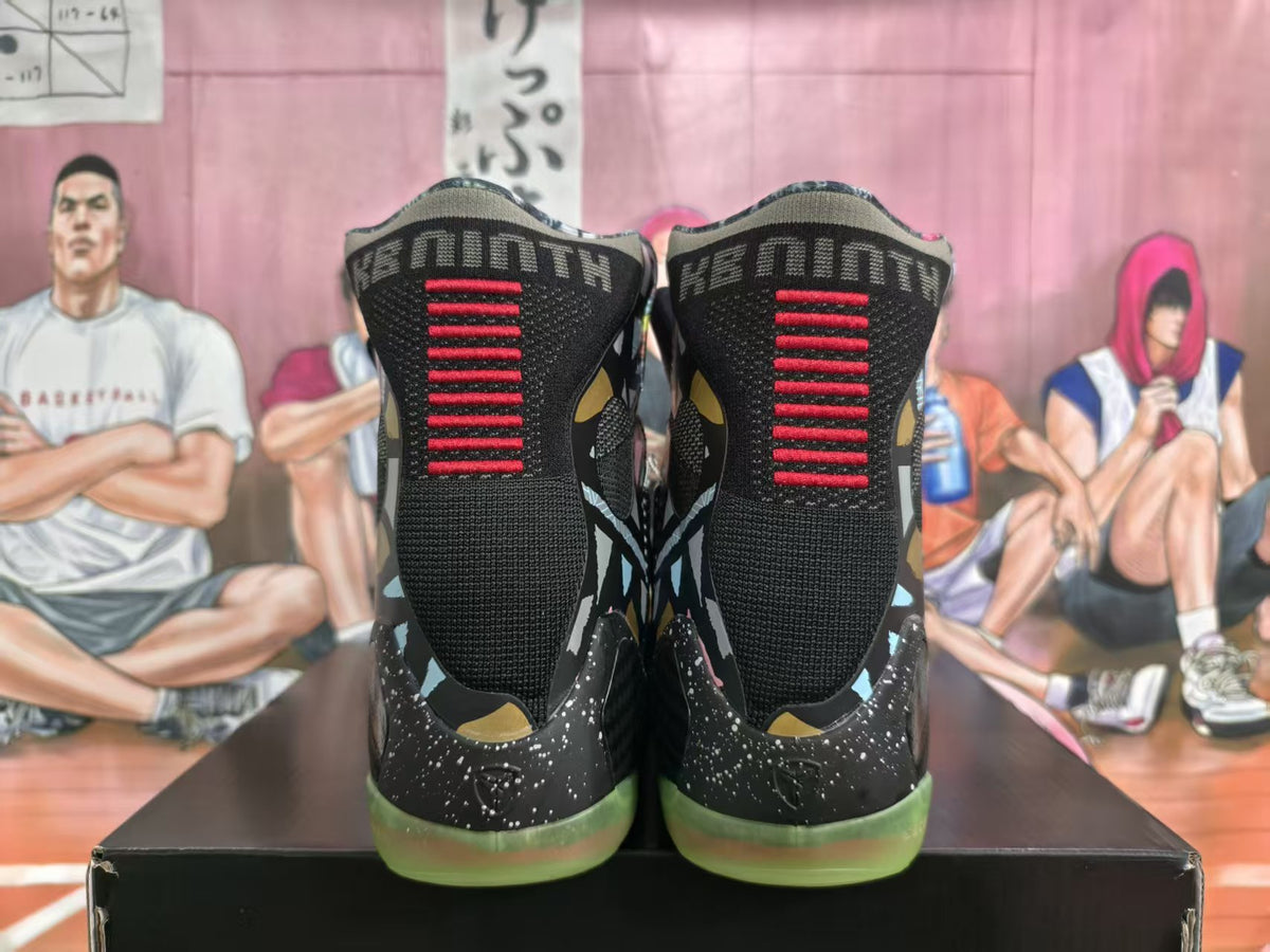 Rear view of black high-top basketball shoes with red heel detailing, speckled black sections, and translucent green outsoles.