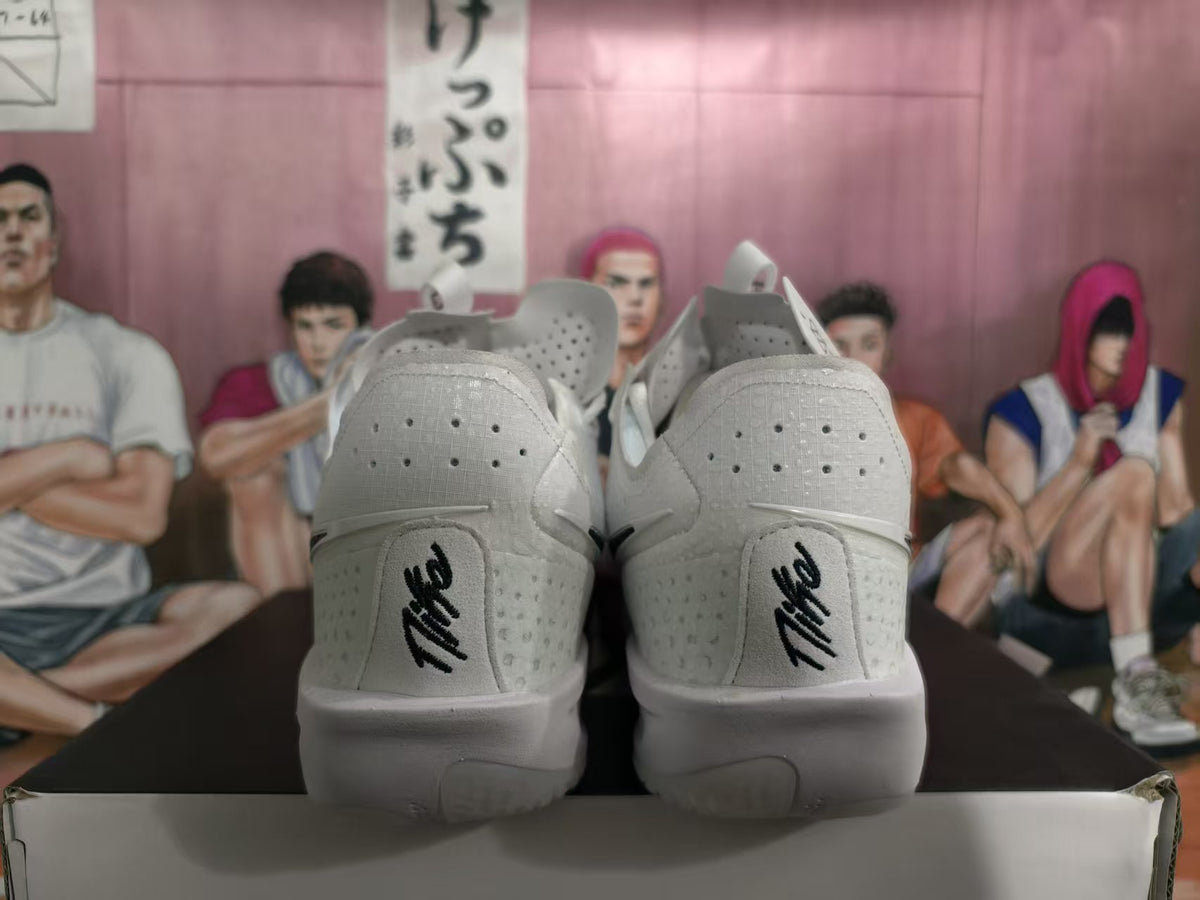 Rear view of white basketball shoes with black heel lettering and light-colored soles.