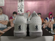 Rear view of white basketball shoes with black heel lettering and light-colored soles.