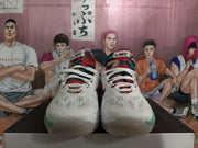 Front view of the white Nike basketball sneakers showing patterned tongues, white laces, and green outsole accents.
