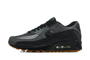 Side view of a black and grey Nike Air Max 90 sneaker with visible heel Air unit and gum outsole